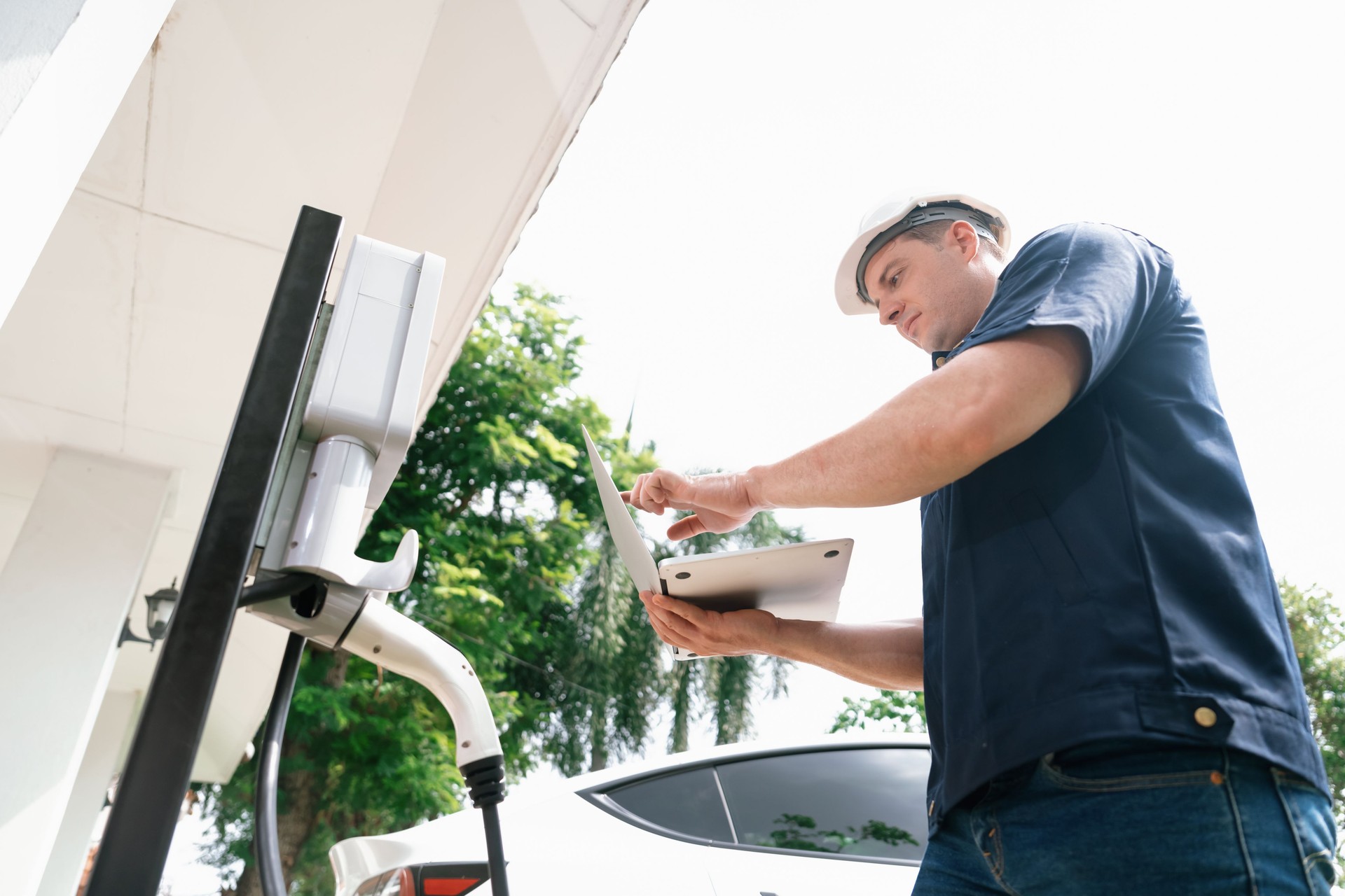 Qualified technician working with laptop for home EV station. Synchronos